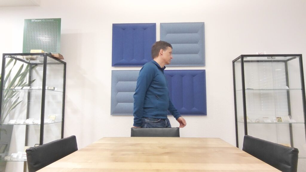 Camera image of an indoor scene with a walking person and static environment